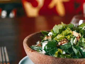 Green salad with walnuts in a wooden bowl