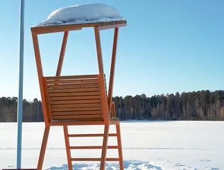 Wooden lifeguard chair in the snow by a frozen lake