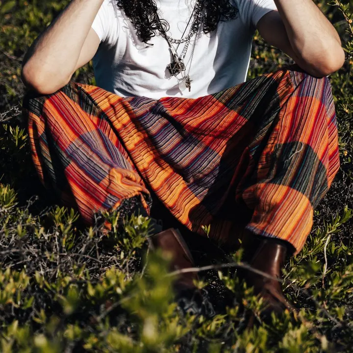 Colourful striped harem pants, worn sitting cross-legged on grass