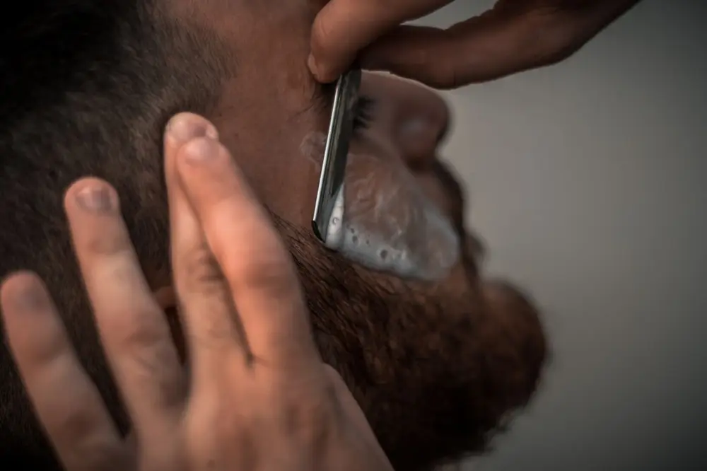 Close-up of a beard being lined up with a straight razor