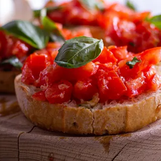 Toasted bread topped with chopped tomatoes and a basil leaf
