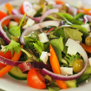 A colourful salad of tomato, cucumber, red onion, peppers, olives and feta