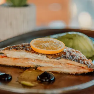 A salmon fillet with an orange slice and olives