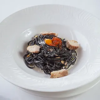 A small nest of black squid ink pasta with pieces of squid