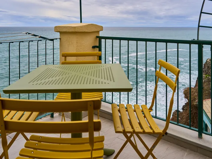 A small table with yellow folding chairs on a terrace above the sea