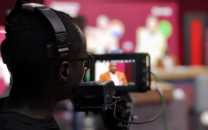 A camera operator with headphones filming in a TV studio