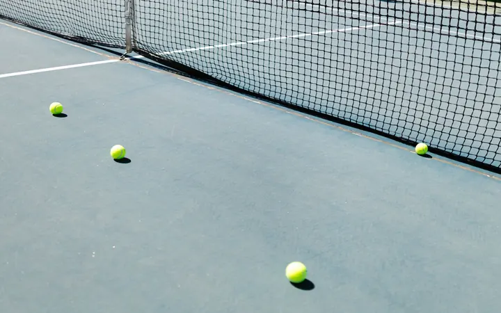 Tennis balls on a hard court next to the net