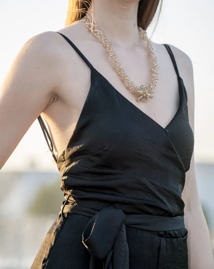Black satin slip dress and crystal necklace, cropped at the shoulders