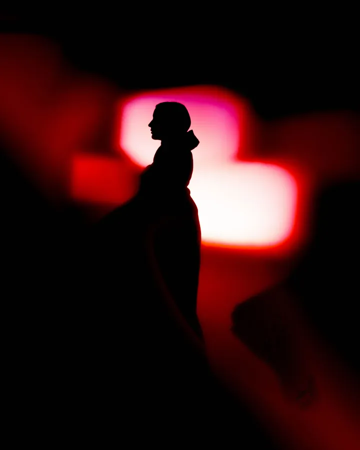 Model in silhouette against blurred red neon light