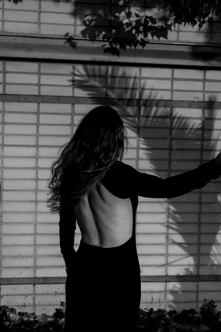 Black-and-white photo of a woman in a black open-back dress, seen from behind