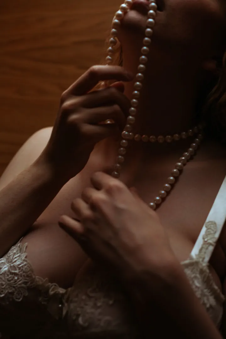 Hands holding long strands of pearls over lace
